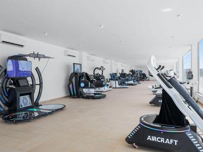 Palestra luminosa e moderna con varie attrezzature per esercizi e grandi finestre.