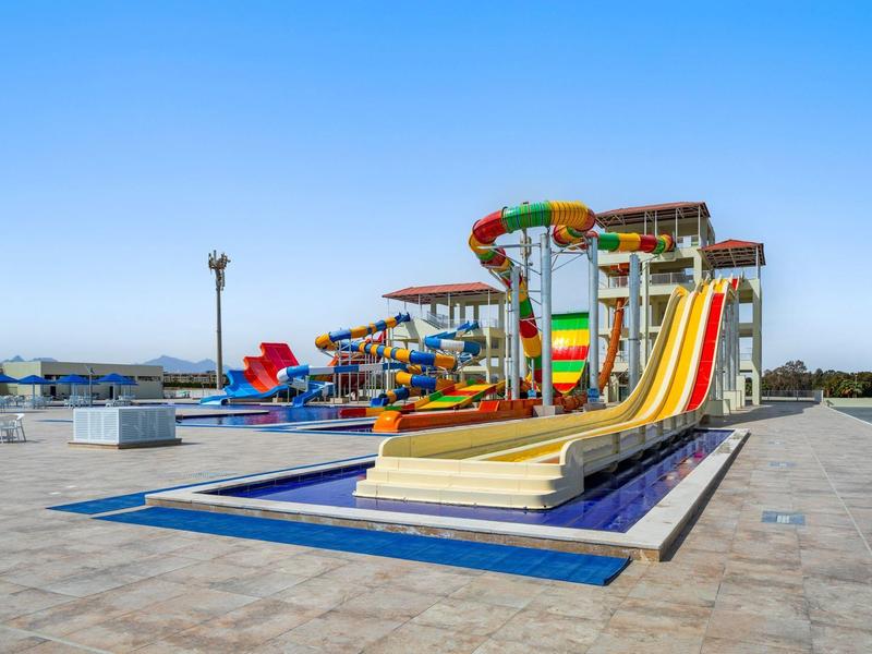 Leere, bunte Wasserrutschen im Außenbereich eines Wasserparks bei klarem Himmel.