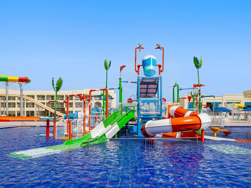 Buntes Wasserspielgerät mit Rutschen in einem Pool unter blauem Himmel.