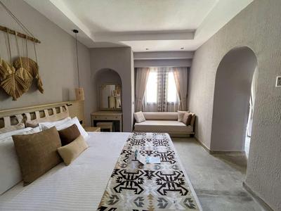 Modern eingerichtetes Schlafzimmer mit Doppelbett, braunen Kissen und Fensterbank mit Sitzkissen.