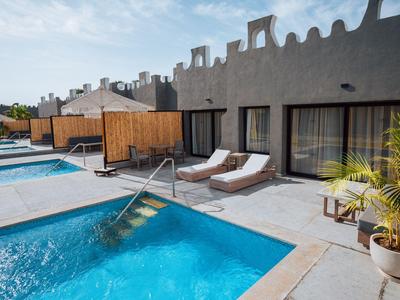Espace extérieur moderne avec piscine, chaises longues et plantes devant les chambres d'hôtel.
