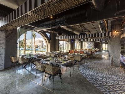 Restaurant moderne avec arcades ouvertes, carreaux à motifs et chaises confortables.