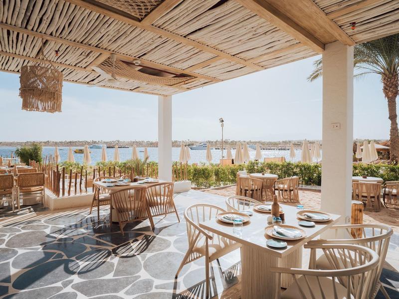 Terraza cubierta con muebles de madera y vista al mar en un hotel.