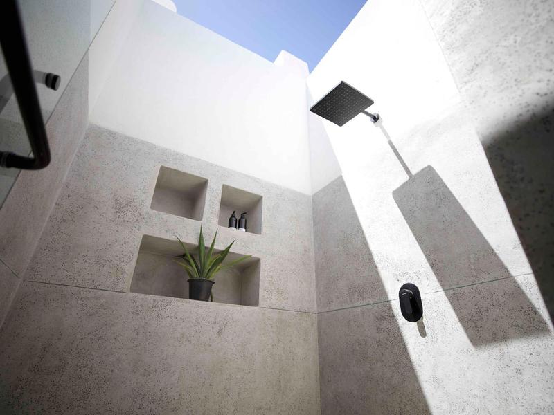 Ducha minimalista y luminosa con nichos integrados y una planta en diseño moderno.