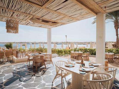 Taras restauracyjny z widokiem na morze, drewniane meble i dach z trzciny.