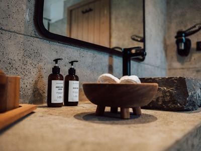 Baño rústico con dispensadores de jabón, un cuenco de piedra y elementos decorativos en la encimera.