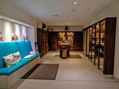 Moderner Hotelbereich mit Sitzbank, Teppichen und Holzregalen mit Produkten.