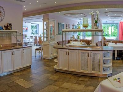 Großes, helles Restaurant mit Holzboden, weißen Möbeln und gedeckten Tischen in angenehmer Atmosphäre.