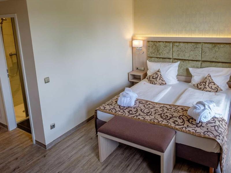 Gemütliches Schlafzimmer mit Doppelbett, dekorativen Kissen, Holzboden und offenem Badezimmer.