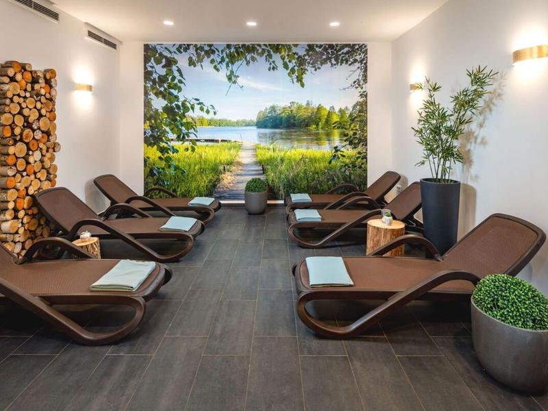 Ontspanningsruimte met bruine ligstoelen, witte handdoeken en een landschapsschilderij aan de muur.