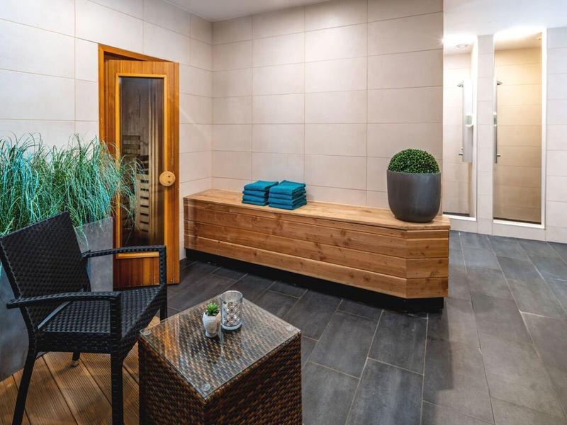 Moderne wellnessruimte met sauna, houten bank, stoel en planten in een hotel.