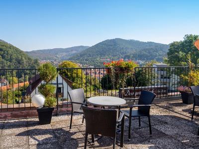 Terrasse mit Sitzbereich und Blick auf bewaldete Hügel unter klarem Himmel