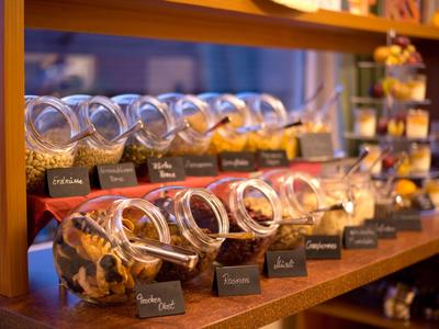 Buffet mit verschiedenen Cerealien und Trockenfrüchten in transparenten Glasbehältern.