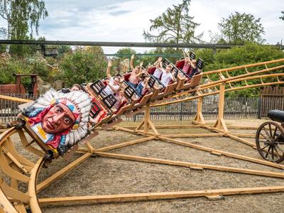 Persone su una montagna russa all'aperto vestite con costumi nativi americani.