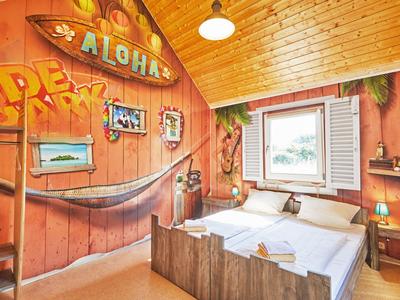 Gemütliches Holzschlafzimmer mit Doppeltbett, Hängematte und Strand-Dekoration.