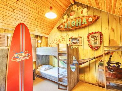 Gemütliches Zimmer mit Holzvertäfelung, Etagenbett, Surfbrett und tropischer Dekoration.