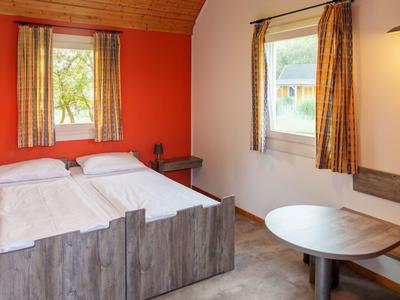 Gemütliches Hotelzimmer mit Doppelbett, Holzmöbeln und Fenster mit Blick ins Grüne.