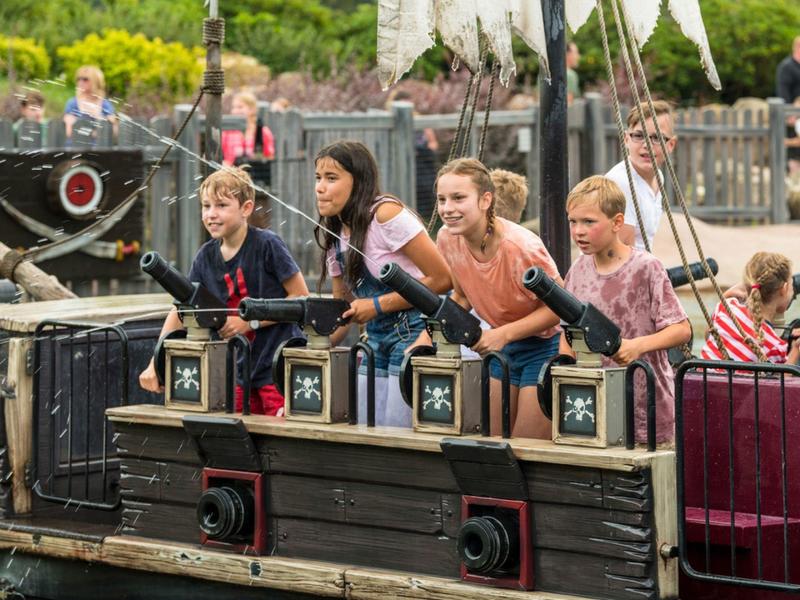 Dzieci wspinają się na statek piracki na zewnątrz w parku rozrywki.