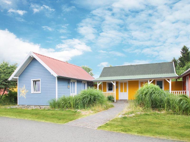 Kolorowe domki wakacyjne z zielonymi ogrodami i niebieskim niebem z chmurami.