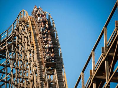 Menschen fahren auf einer Holzachterbahn bei klarem Himmel