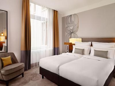 Modern eingerichtetes Hotelzimmer mit zwei Einzelbetten, Sessel und großem Spiegel