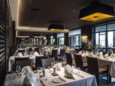 Elegantes Hotelrestaurant mit weiß gedeckten Tischen und moderner Beleuchtung.