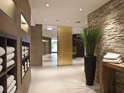 Moderner Flur mit Steinwand, grüner Pflanze und weißen Handtüchern in Nischen und auf Tisch.