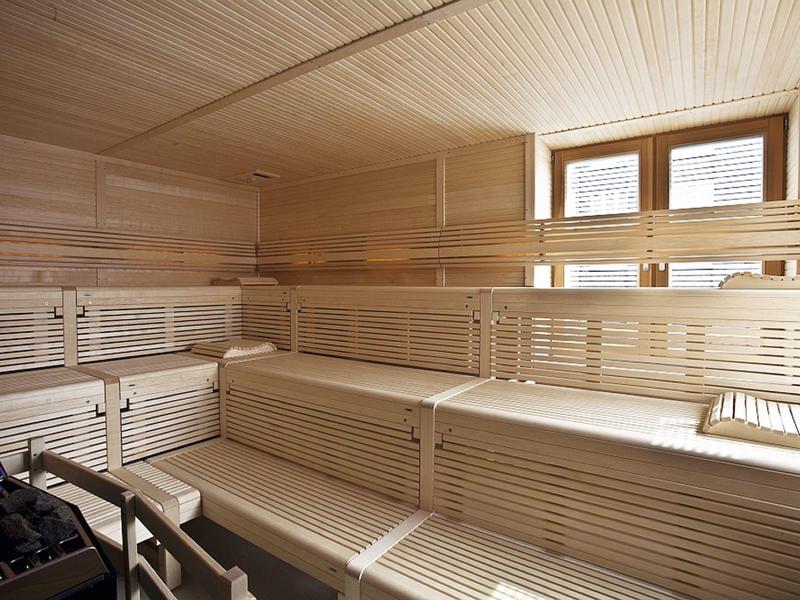 Helle, moderne Sauna mit mehrstufigen Holzbänken und großem Fenster für Tageslicht.