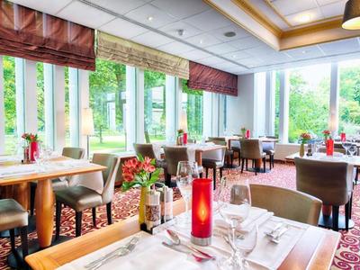 Helles Restaurant mit großen Fenstern, roten Kerzen und elegant gedeckten Tischen.