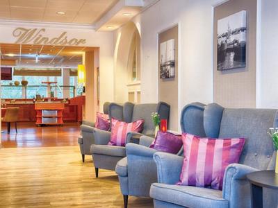 Gemütlicher Wartebereich mit blauen Sesseln und pink gestreiften Kissen in einem Hotel.