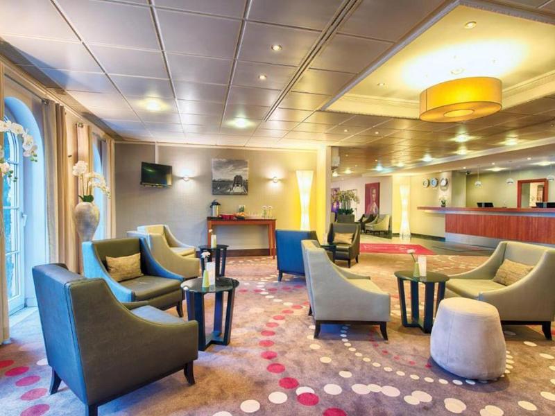 Helle Hotel-Lounge mit moderner Einrichtung, Sesseln und gemustertem Teppichboden.