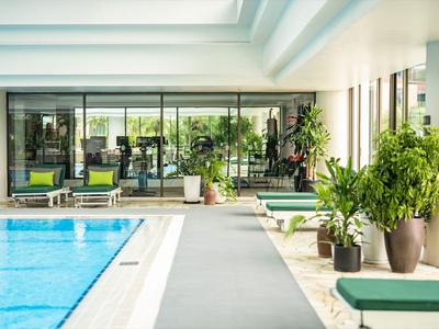 Moderner Wellnessbereich mit Schwimmbad, Liegestühlen und vielen Pflanzen.