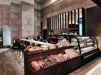 Moderne Bäckerei mit Holztheke, Glasvitrine voller Backwaren und Barhockern am Tresen.