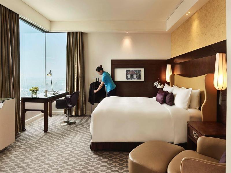 Modernes Hotelzimmer mit großem Bett, Schreibtisch, Fernseher und Panoramafenster mit Meerblick.