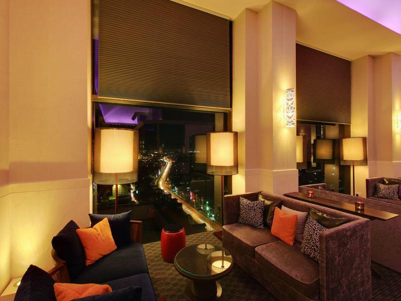 Gemütlicher Wohnzimmerbereich mit Sofas, Kissen und warmem Licht in abendlicher Atmosphäre.