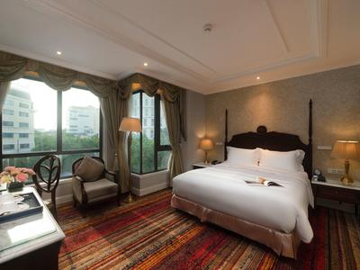 Gezellige hotelkamer met tweepersoonsbed, fauteuils en groot raam met uitzicht op de stad.