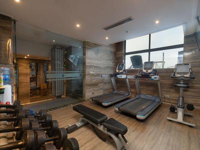 Modernes Fitnessstudio mit Laufbändern, Hanteln und Trainingsgeräten in einem hellen Raum.