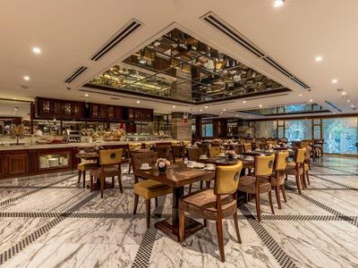 Elegant hotelrestaurant met marmeren vloer, houten meubels en een decoratieve spiegel aan het plafond.