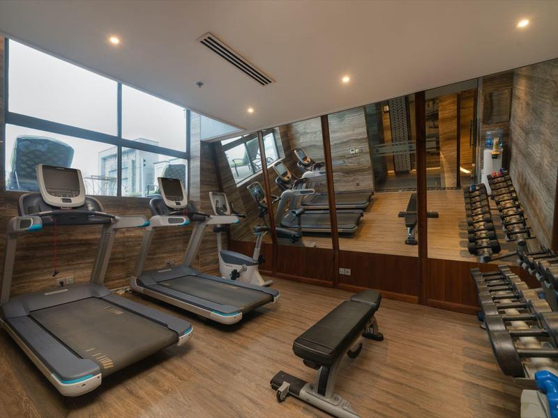 Moderne fitnessruimte met loopbanden, fietsen, halters en spiegelwand in een hotel.