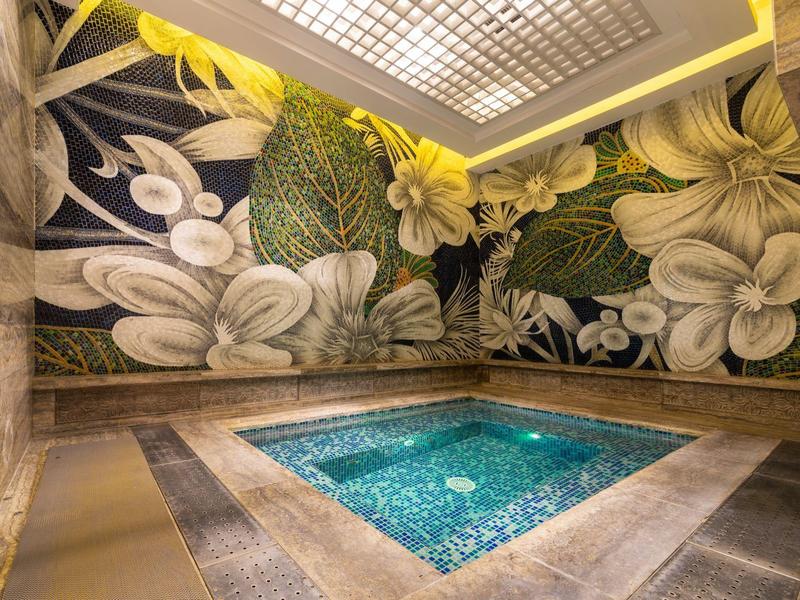 Luxe binnenwhirlpool met bloemrijke wanddecoratie en sfeerverlichting.