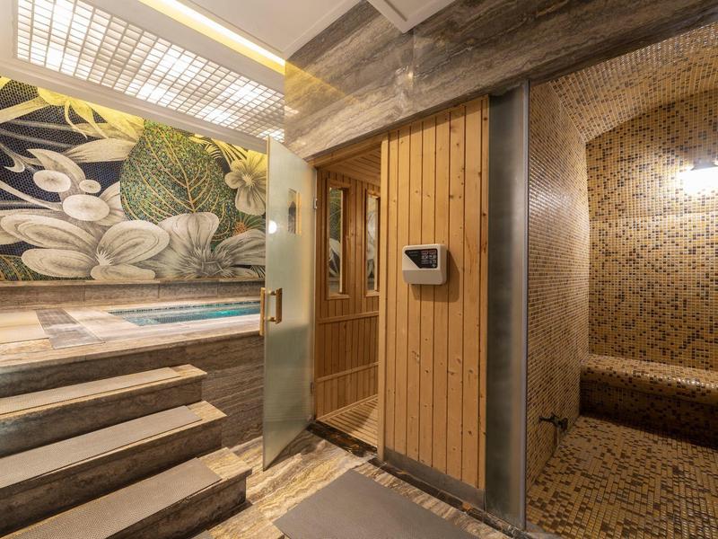Moderne wellnessruimte met sauna, trap en decoratief wandontwerp.