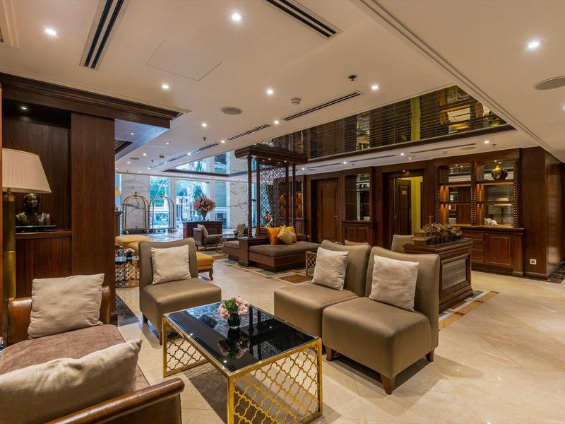 Elegante hotel lobby met comfortabele stoelen, glastafels en warme houten decoratie.