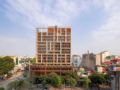 Bâtiment d'hôtel moderne à plusieurs étages avec façade en verre en milieu urbain en plein jour.