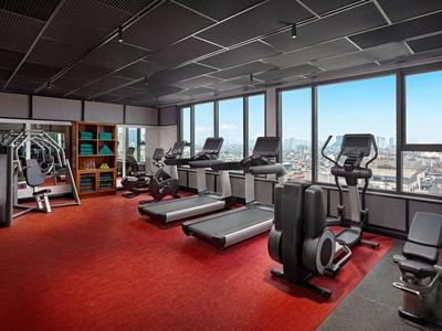 Modernes Fitnessstudio mit Laufbändern und großen Fenstern mit Stadtblick.