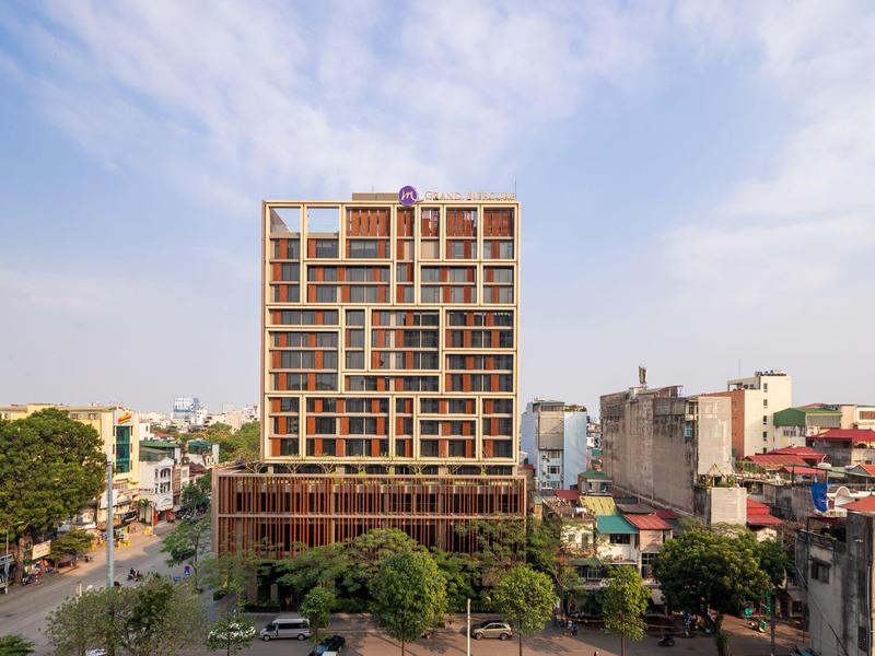 Bâtiment d'hôtel moderne à plusieurs étages avec façade en verre en milieu urbain en plein jour.