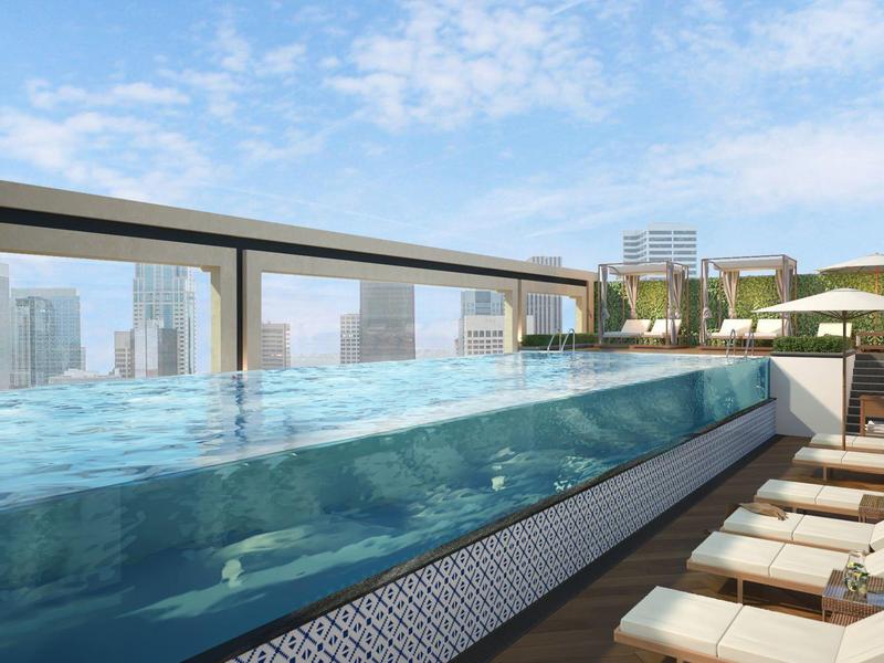 Piscine à débordement moderne sur le toit avec chaises longues et vue sur la ville.