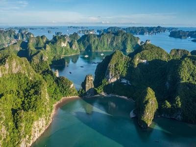 Grüne Kalksteinfelsen umgeben klares, blaues Wasser in einer tropischen Bucht.