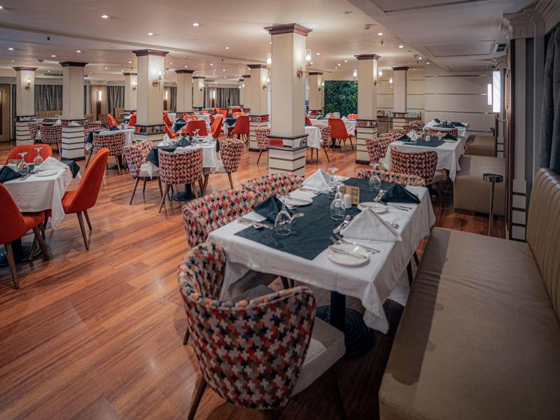 Wnętrze restauracji hotelowej z elegancko nakrytymi stołami i wygodnymi krzesłami.