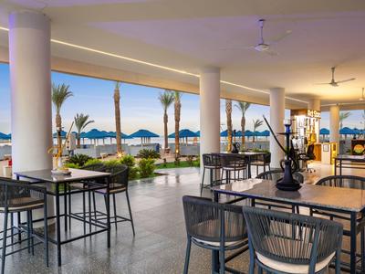 Modern outdoor hotel area with seating and a view of the beach and sea.
