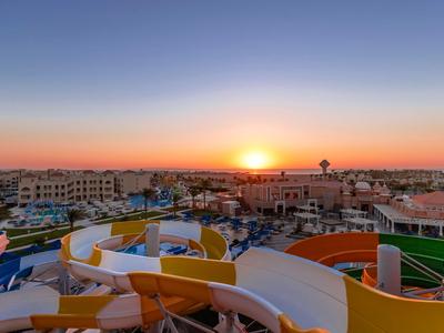 Coucher de soleil sur une ville avec des toboggans aquatiques colorés et des bâtiments au premier plan.